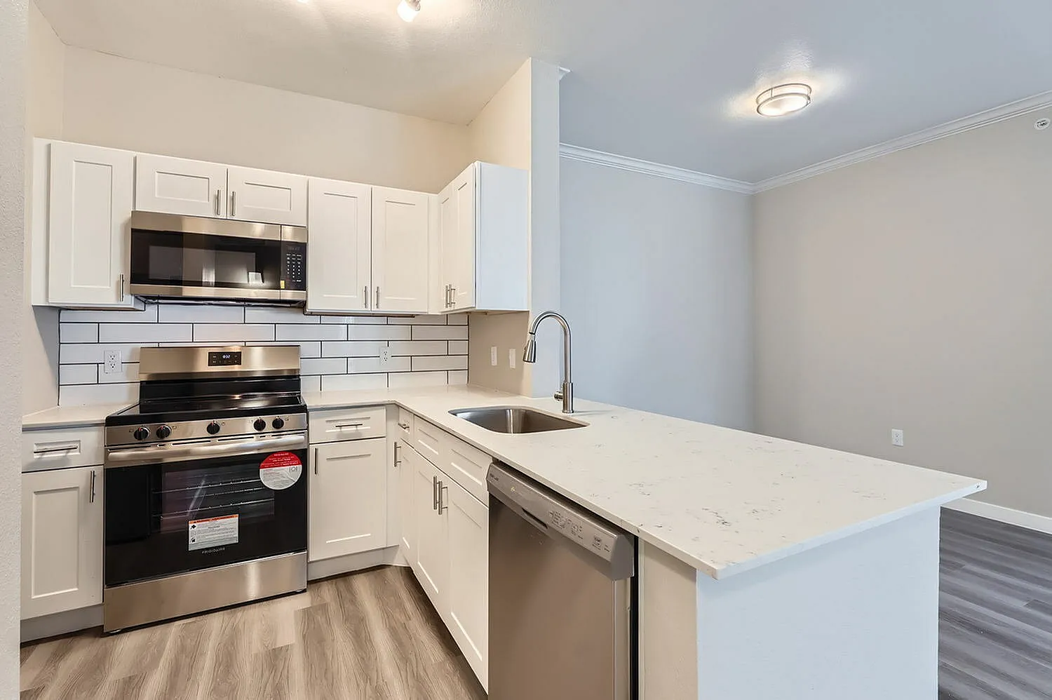 Kitchen, white shaker cabinetry, quartz countertops, stainless appliances, wood-style plank flooring