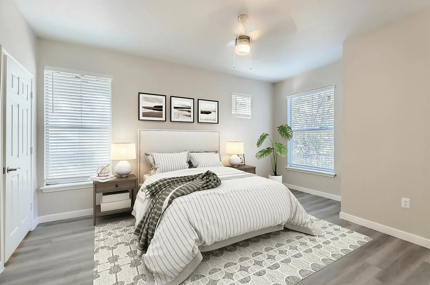 Primary bedroom, wood-style plank flooring, dual nightstands with lamps, geometric area rug