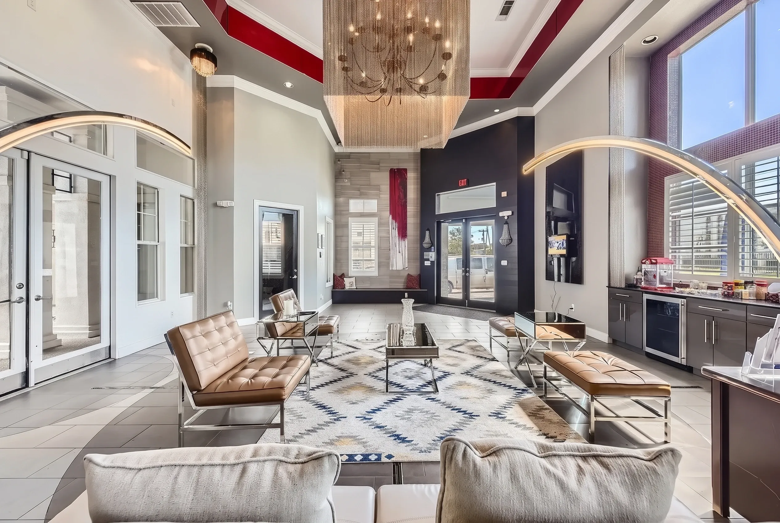 Upscale lobby with contemporary furnishings, two-story ceiling with chandelier, wood-style plank flooring, modern seating areas