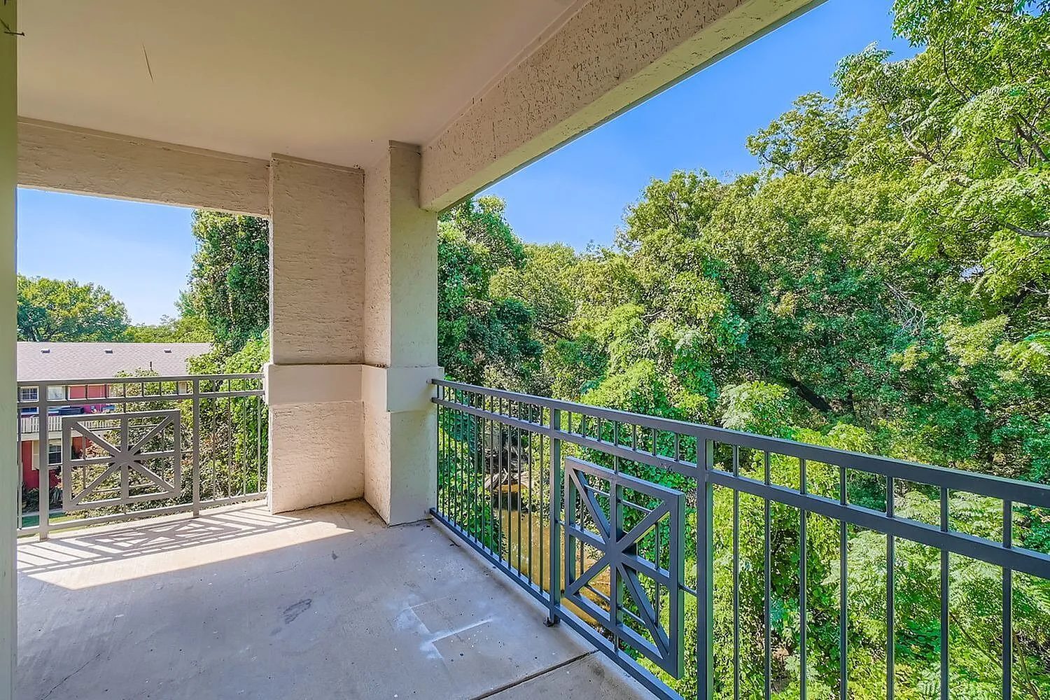 Balcony, metal railing, concrete flooring, green tree canopy views