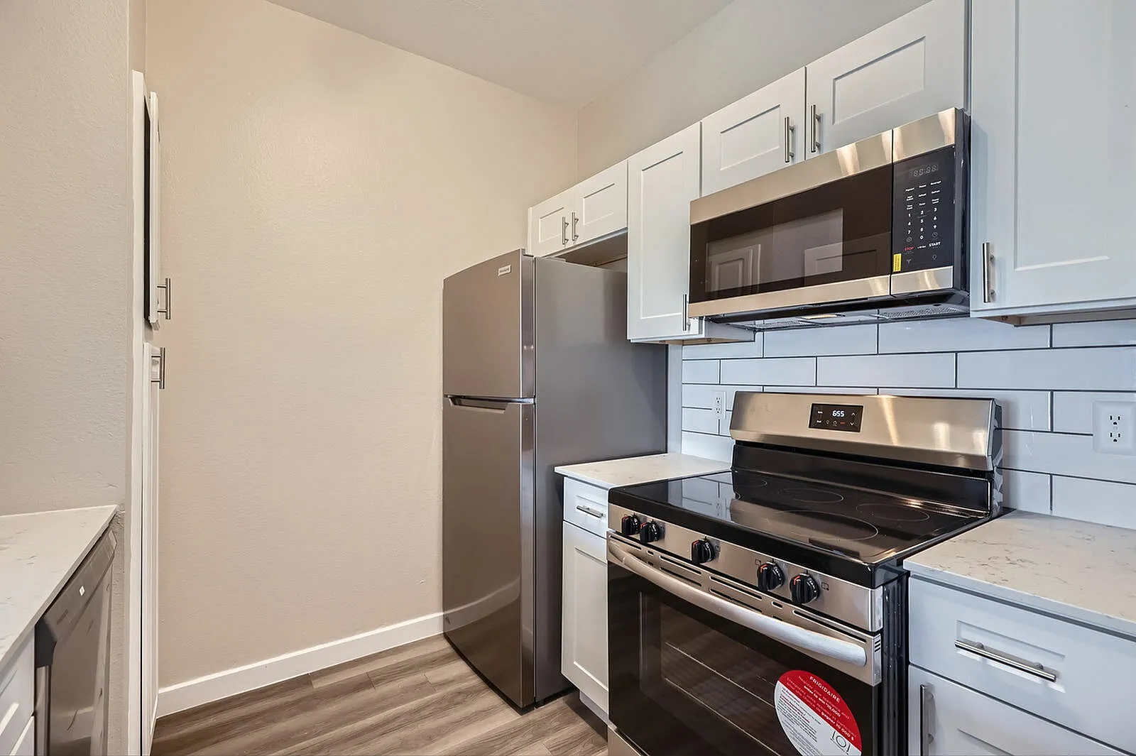 Kitchen, white shaker cabinetry, subway tile backsplash, stainless steel appliances, wood-style plank flooring