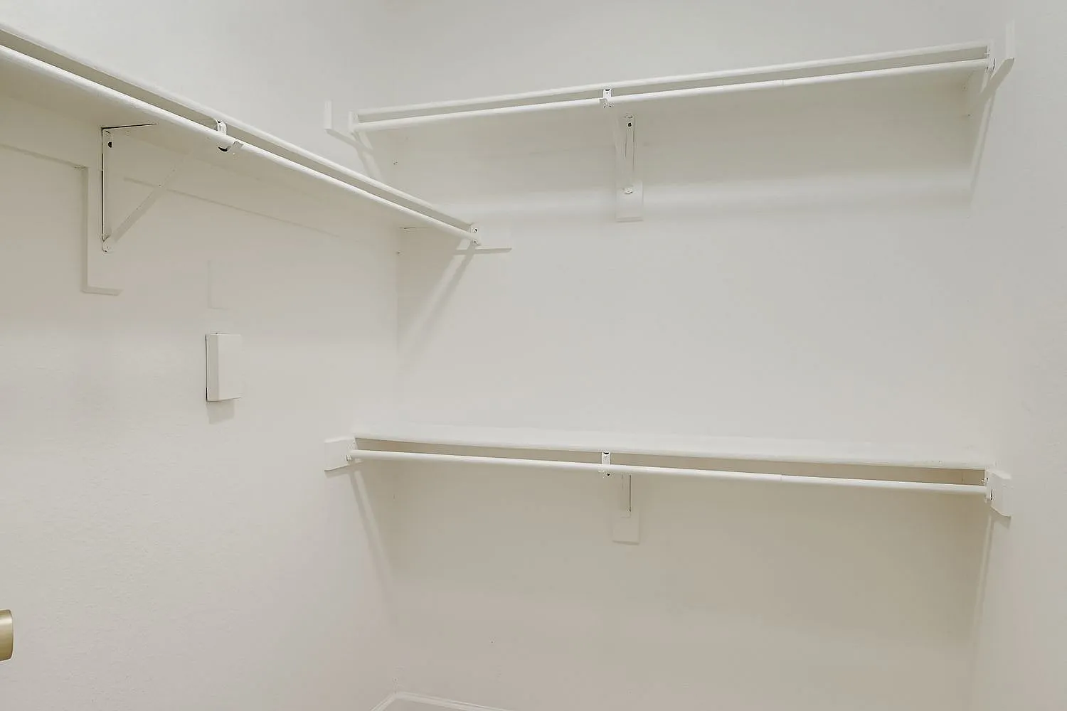 Closet, white built-in shelves with brackets, metal rods, white walls