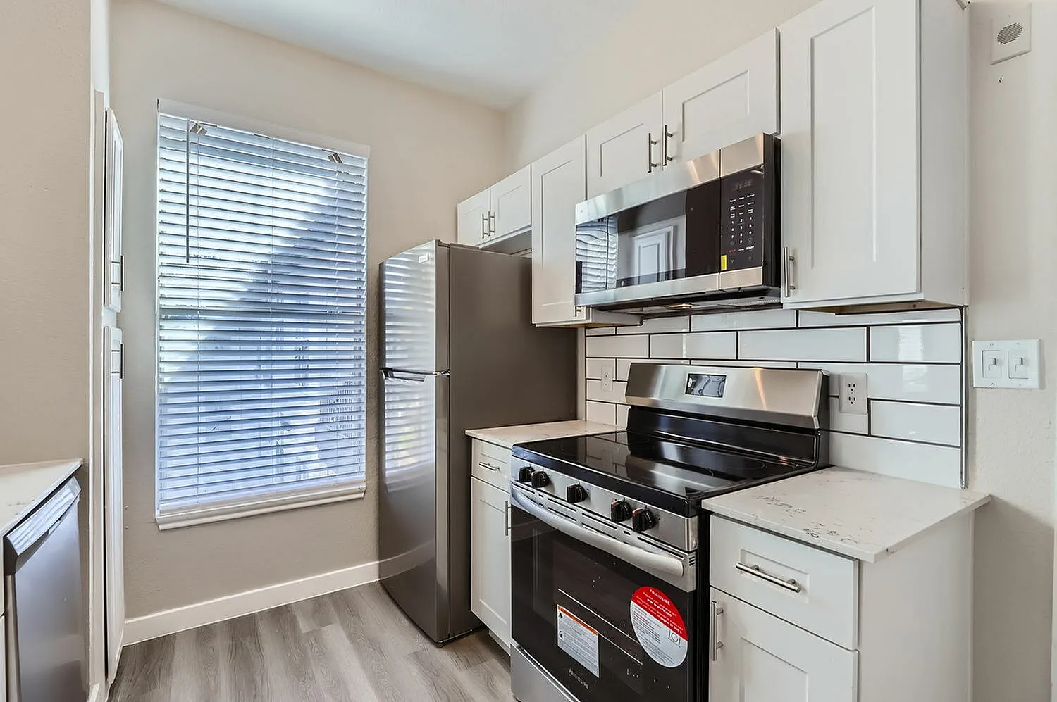 Kitchen, white shaker cabinetry, subway tile backsplash, stainless steel appliances, wood-style plank flooring