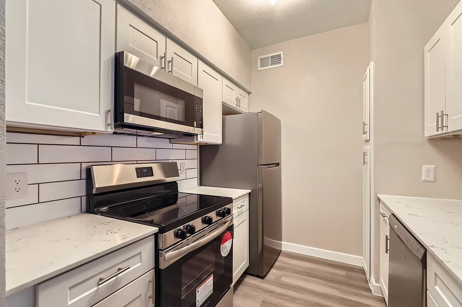 Kitchen, white shaker cabinetry, quartz countertops, stainless appliances, subway tile backsplash, wood-style plank flooring