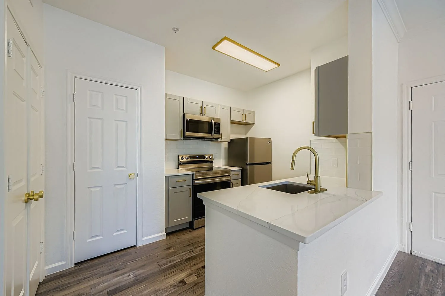 Kitchen, white cabinetry, quartz countertops, stainless appliances, wood-style plank flooring