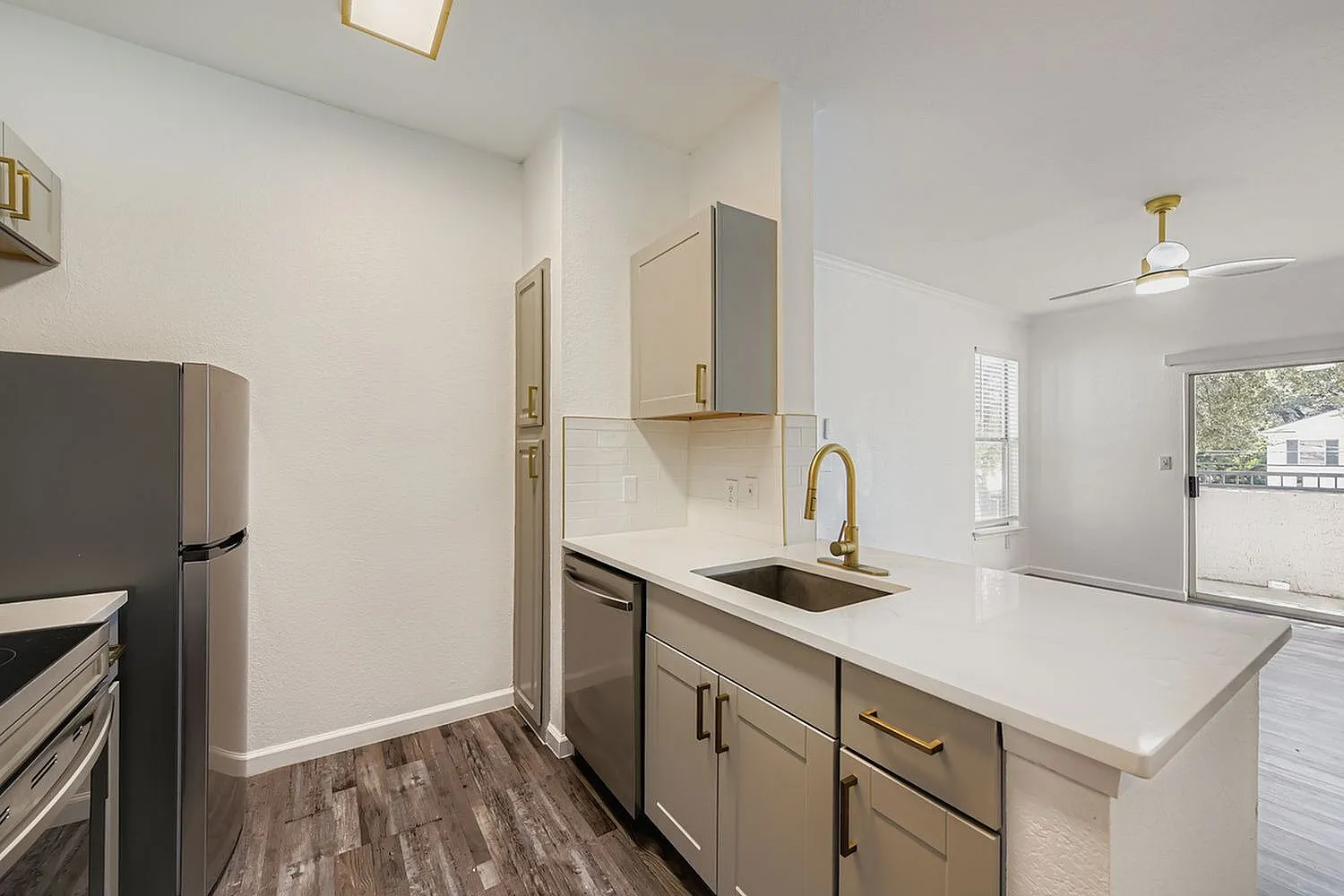 Kitchen, white quartz countertops, stainless steel appliances, wood-style plank flooring, gold fixtures