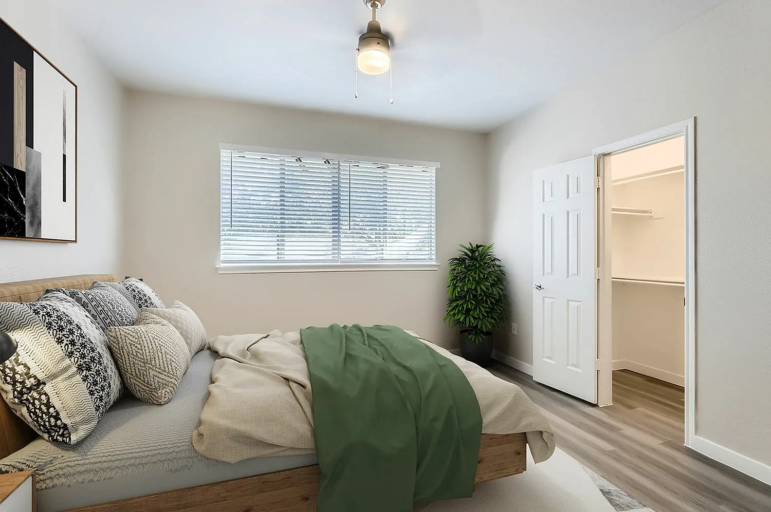Primary bedroom, wood-style plank flooring, patterned pillows, green bedding, window with blinds