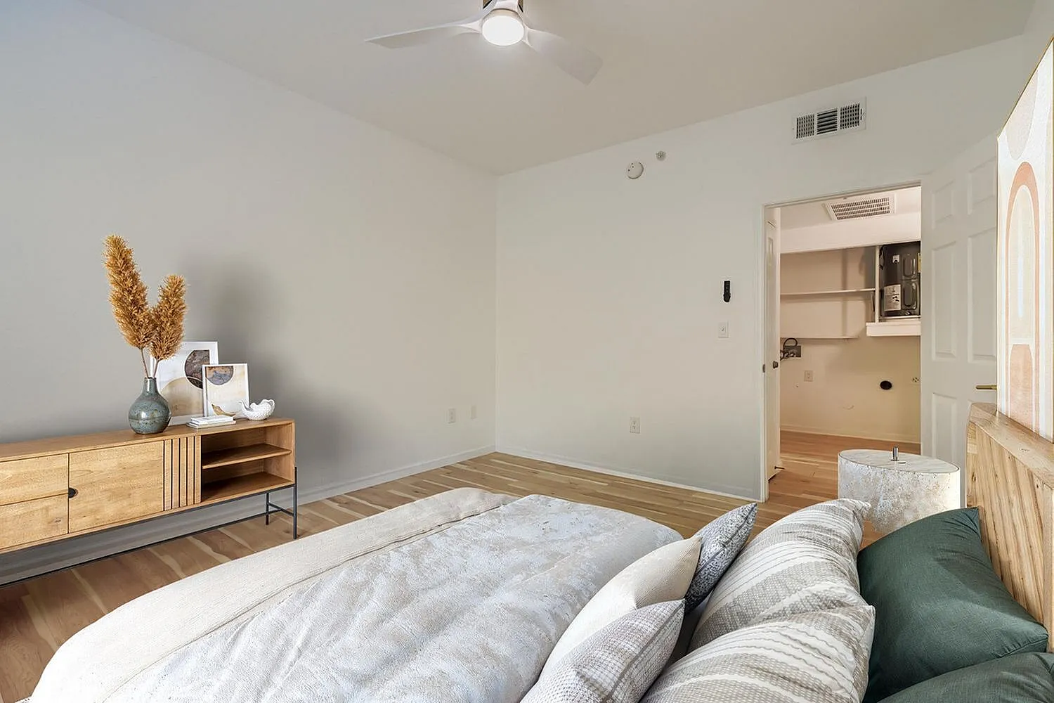 Primary bedroom, wood-style plank flooring, ceiling fan, built-in shelving, bed with striped and green pillows