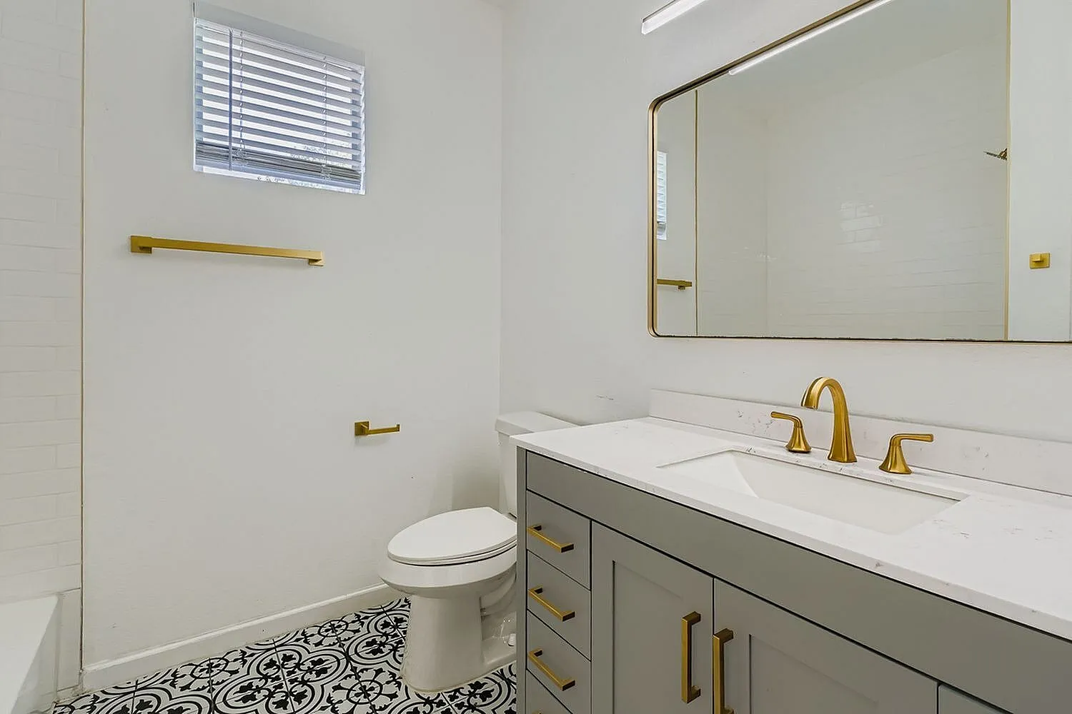 Primary bathroom, white quartz countertops, gold faucet and hardware, geometric floor tile