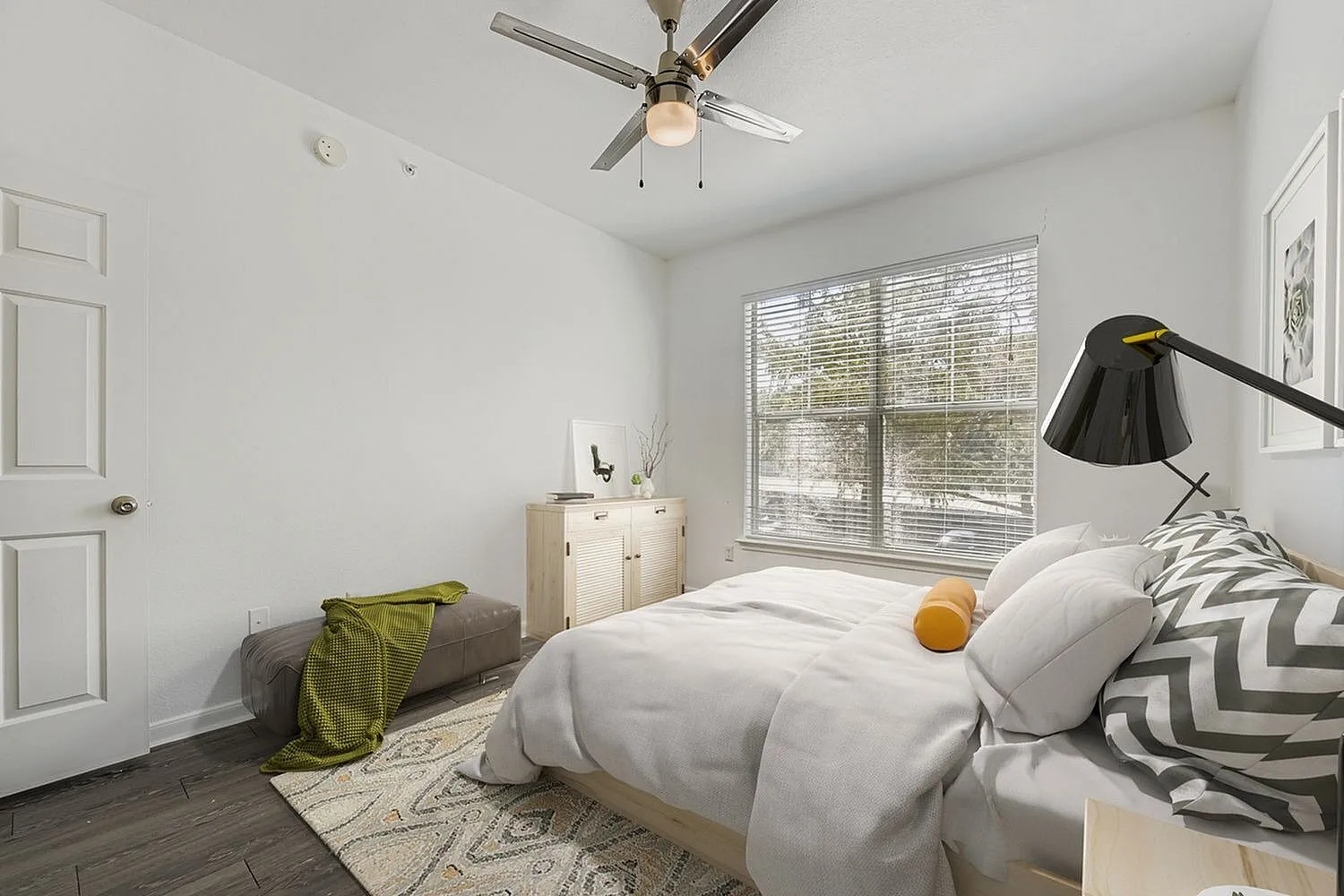 Primary bedroom, wood-style plank flooring, ceiling fan with light, large window with blinds