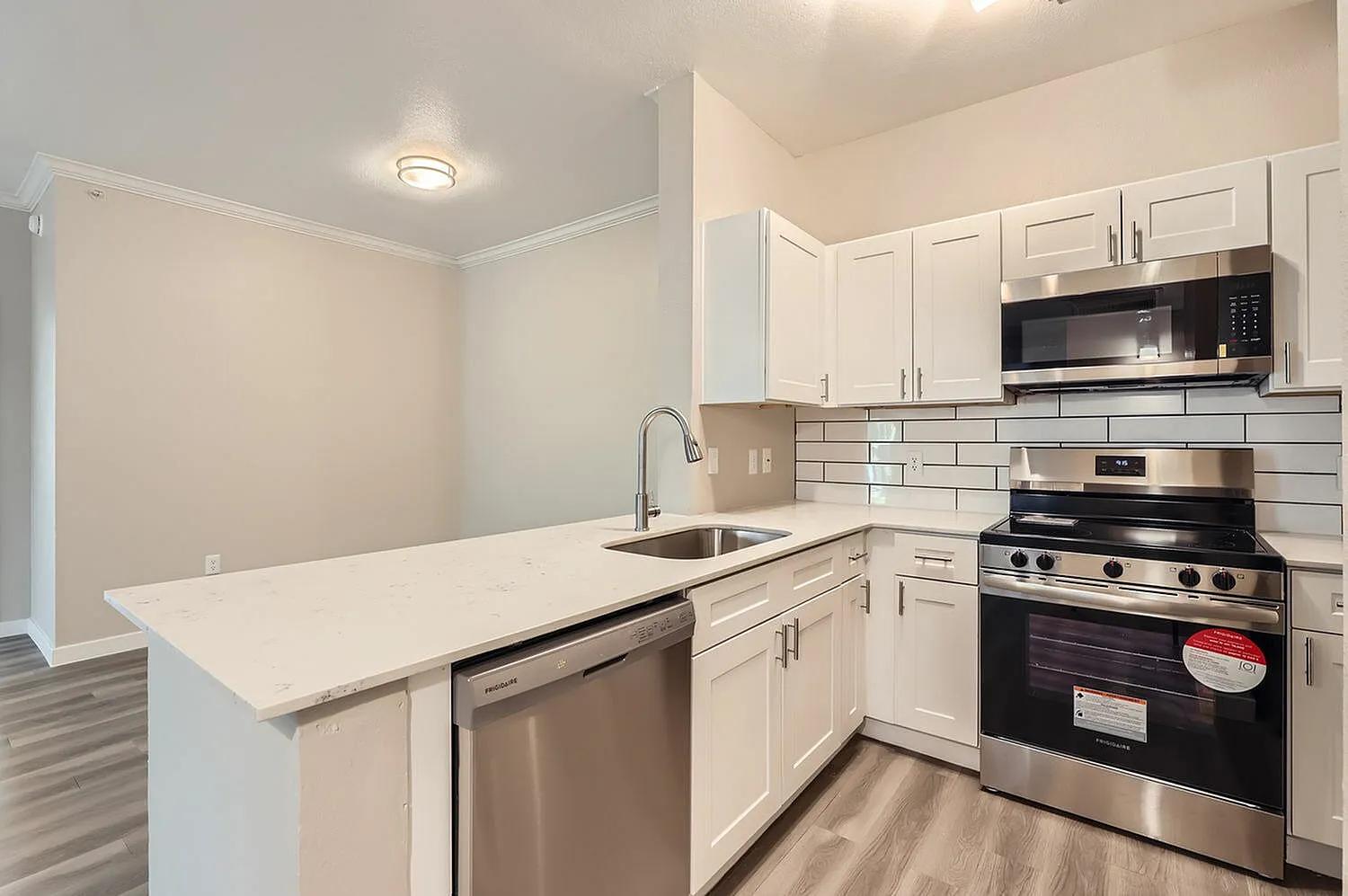 Kitchen, white shaker cabinetry, quartz countertops, stainless appliances, wood-style plank flooring