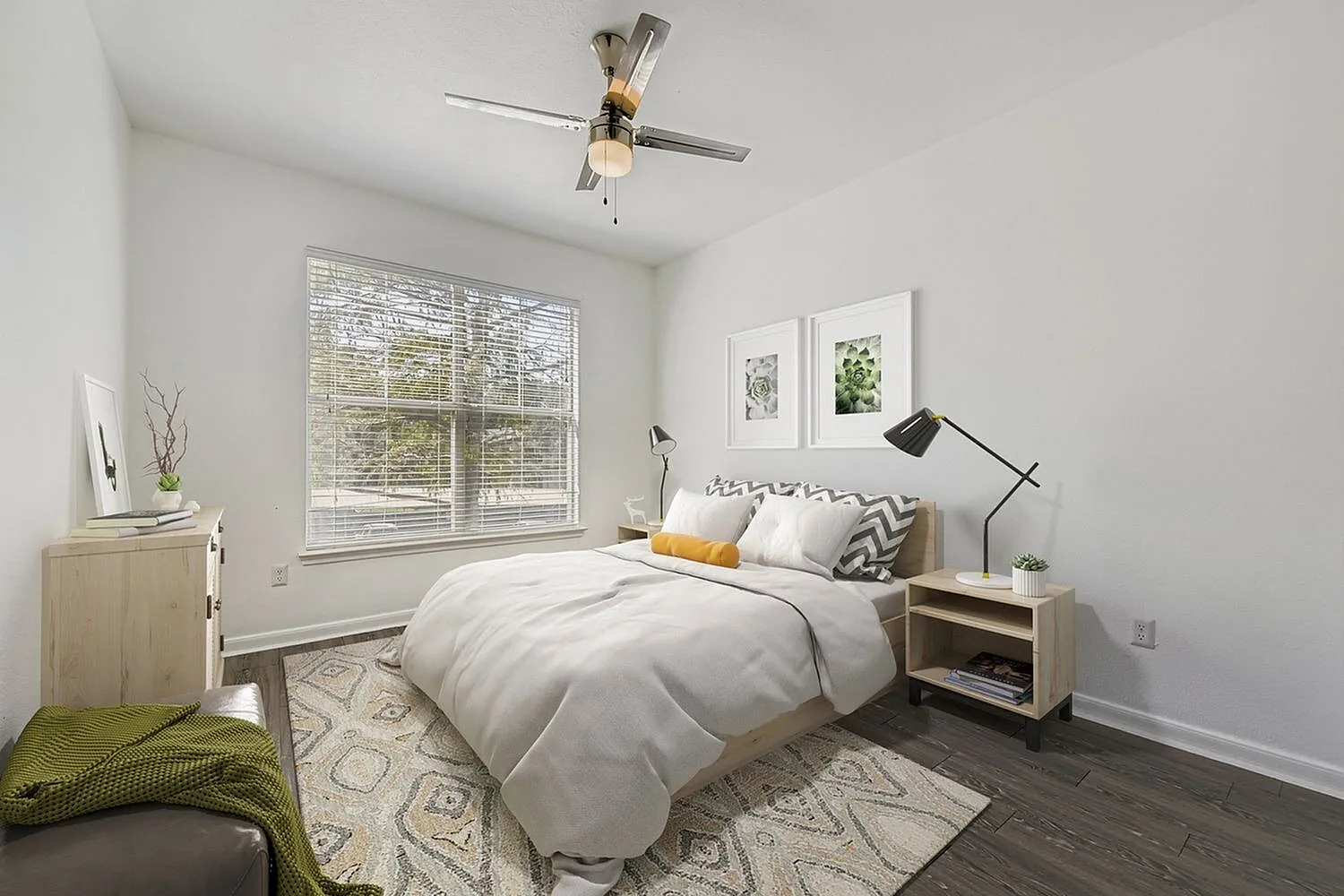Bedroom, wood-style plank flooring, ceiling fan, large window with blinds, framed wall art