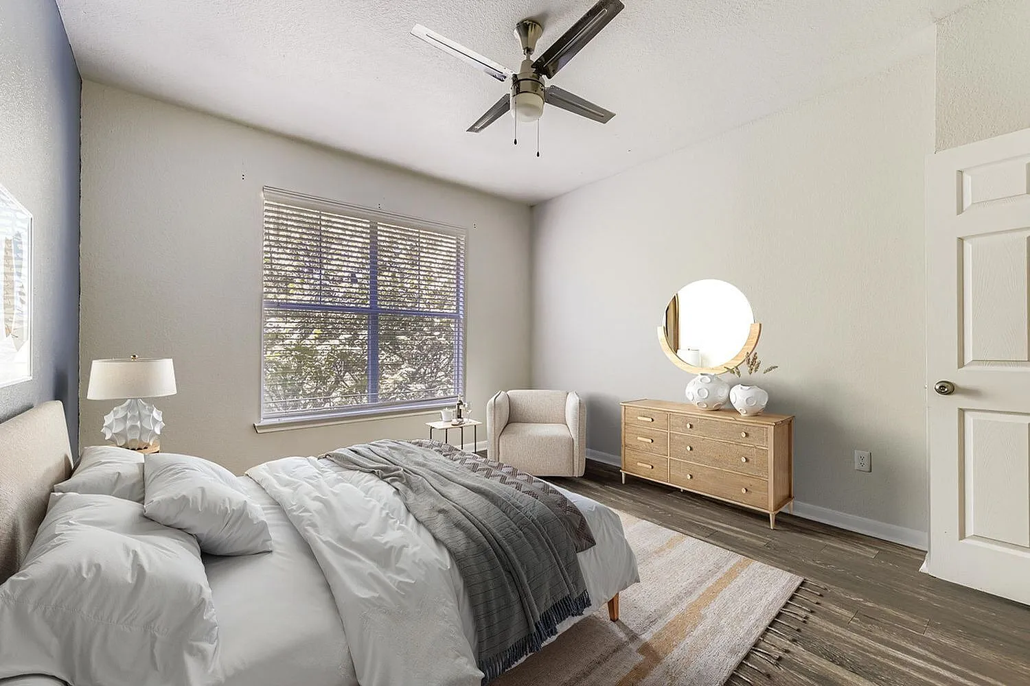 Primary bedroom, wood-style plank flooring, ceiling fan, large window with blinds, wood dresser