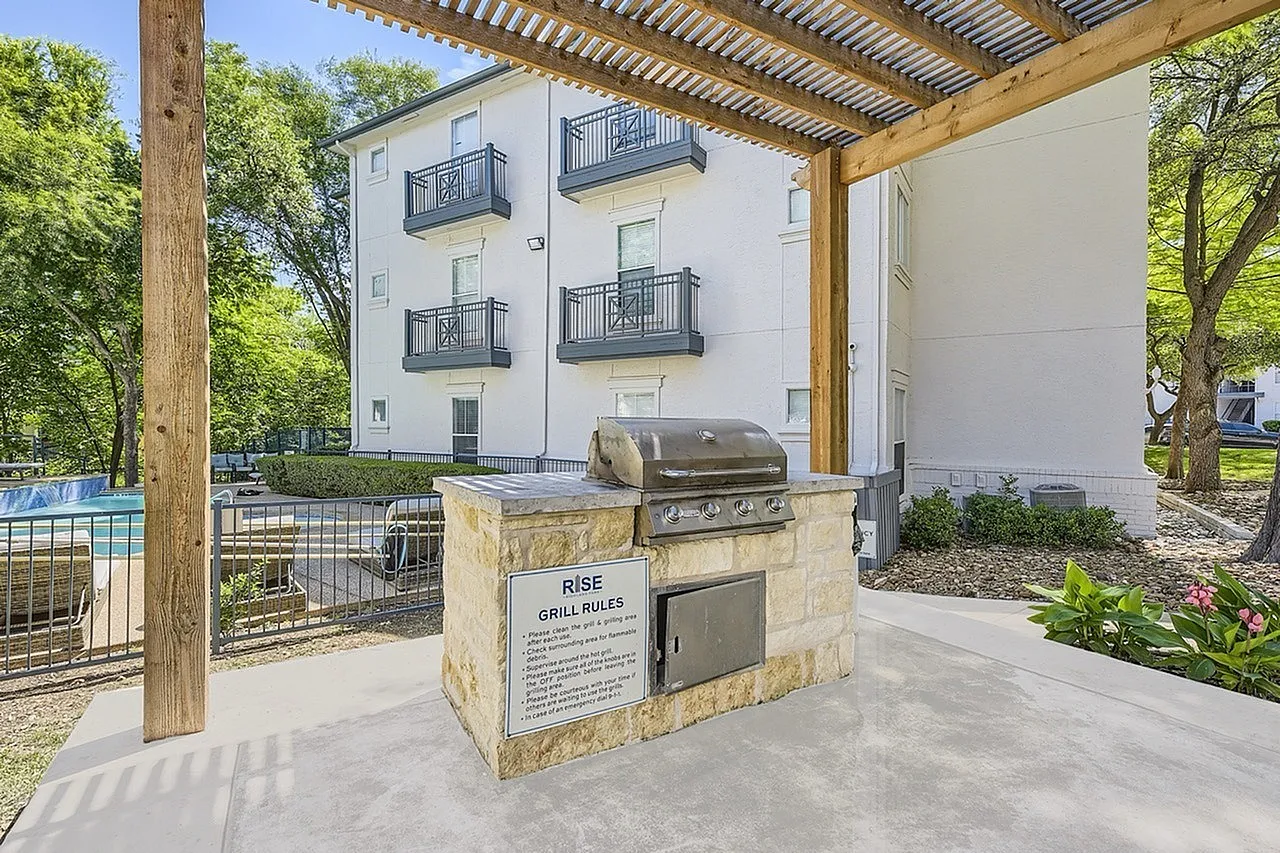 Outdoor patio with built-in grill, pergola, residential building, pool, landscaping