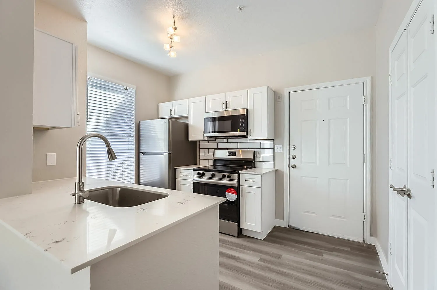 Kitchen, white shaker cabinetry, quartz countertops, stainless appliances, wood-style plank flooring