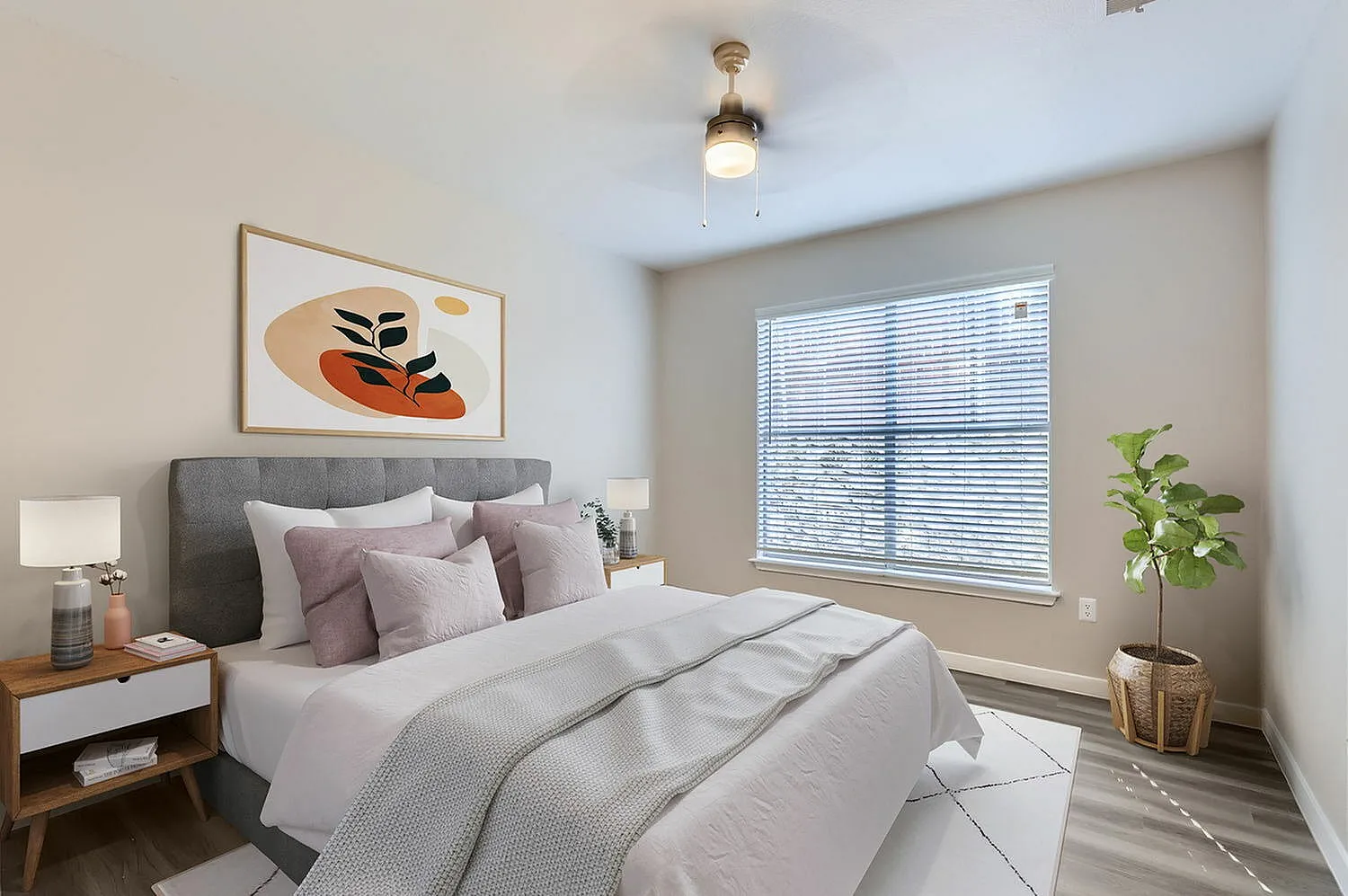 Primary bedroom, gray upholstered headboard, white bedding with throw pillows, wood-style plank flooring, large window with blinds