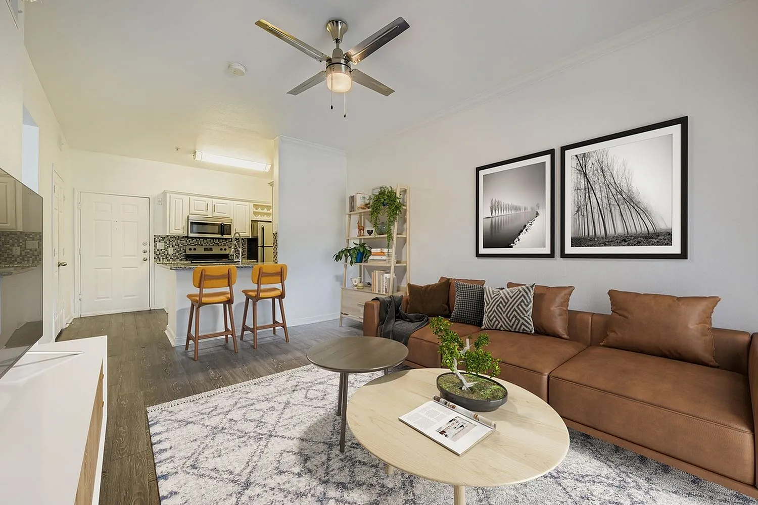 Living room with cognac leather sofa, wood-style plank flooring, ceiling fan, framed wall art