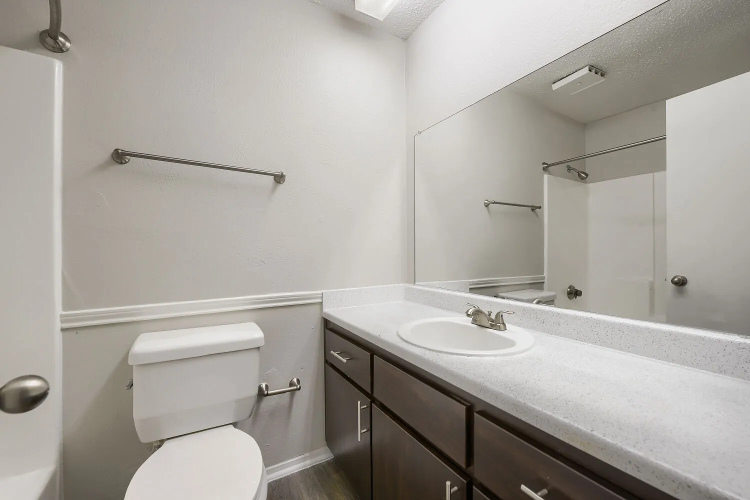 Primary bathroom, dark vanity cabinetry, towel bar, wide mirror