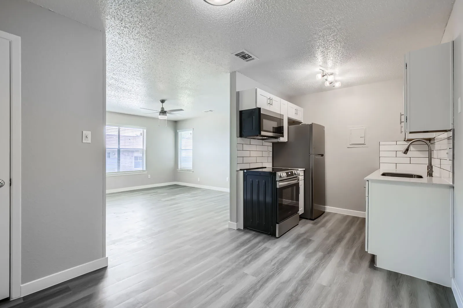 Kitchen with white shaker cabinets, quartz countertops, stainless steel appliances, view into breakfast area