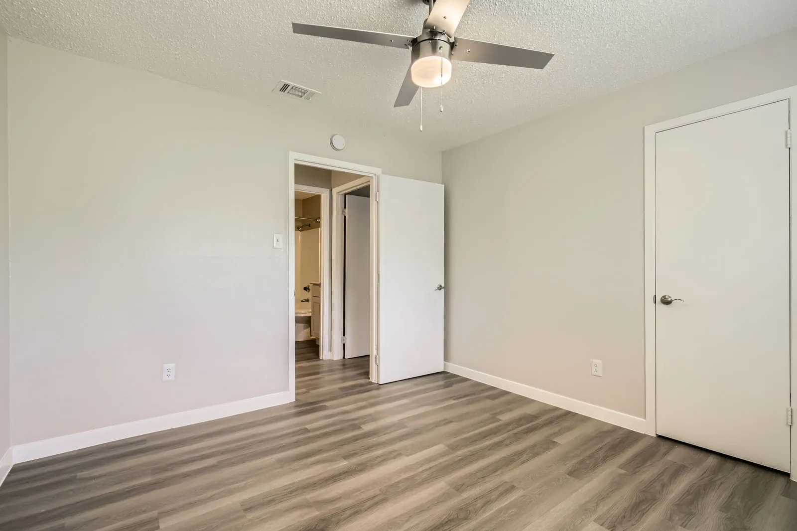 Second bedroom, wood-style plank flooring, ceiling fan, closet