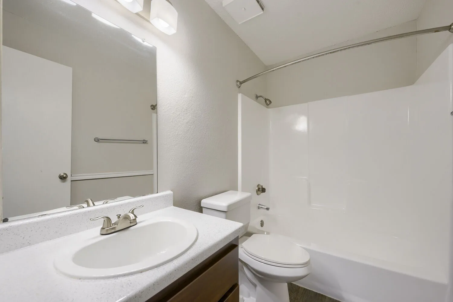 Hallway bathroom, tub-shower combo, vanity, wall-mounted light fixture