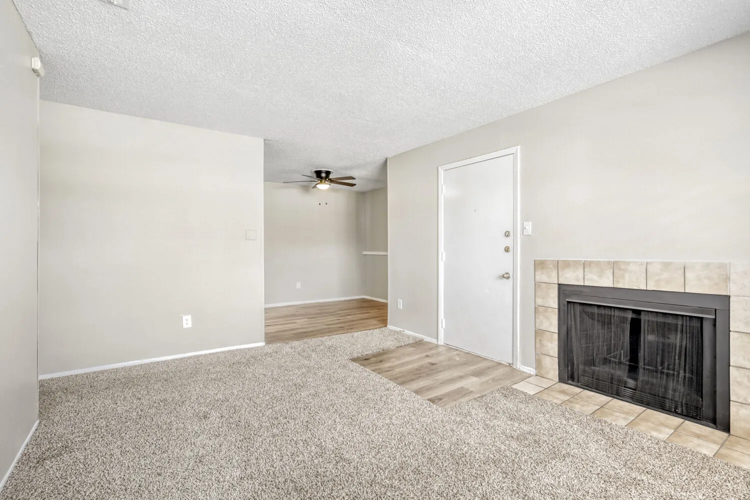 Carpeted living area, tile-front fireplace, front entry door, ceiling fan in dining nook