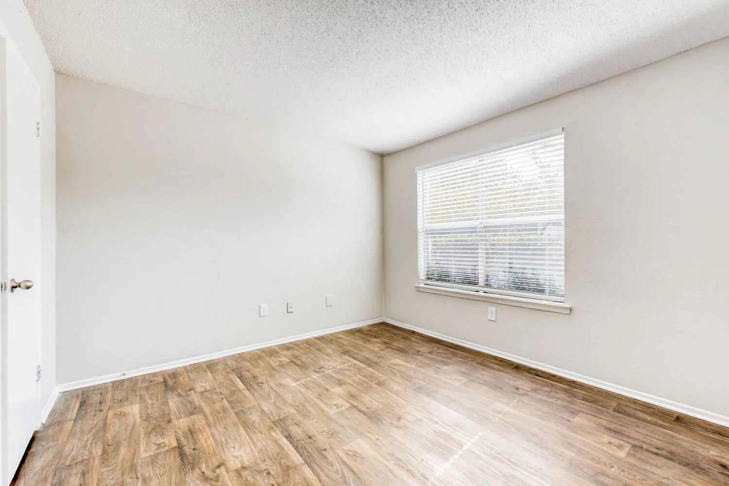Bedroom with wood-style plank flooring, window with natural light