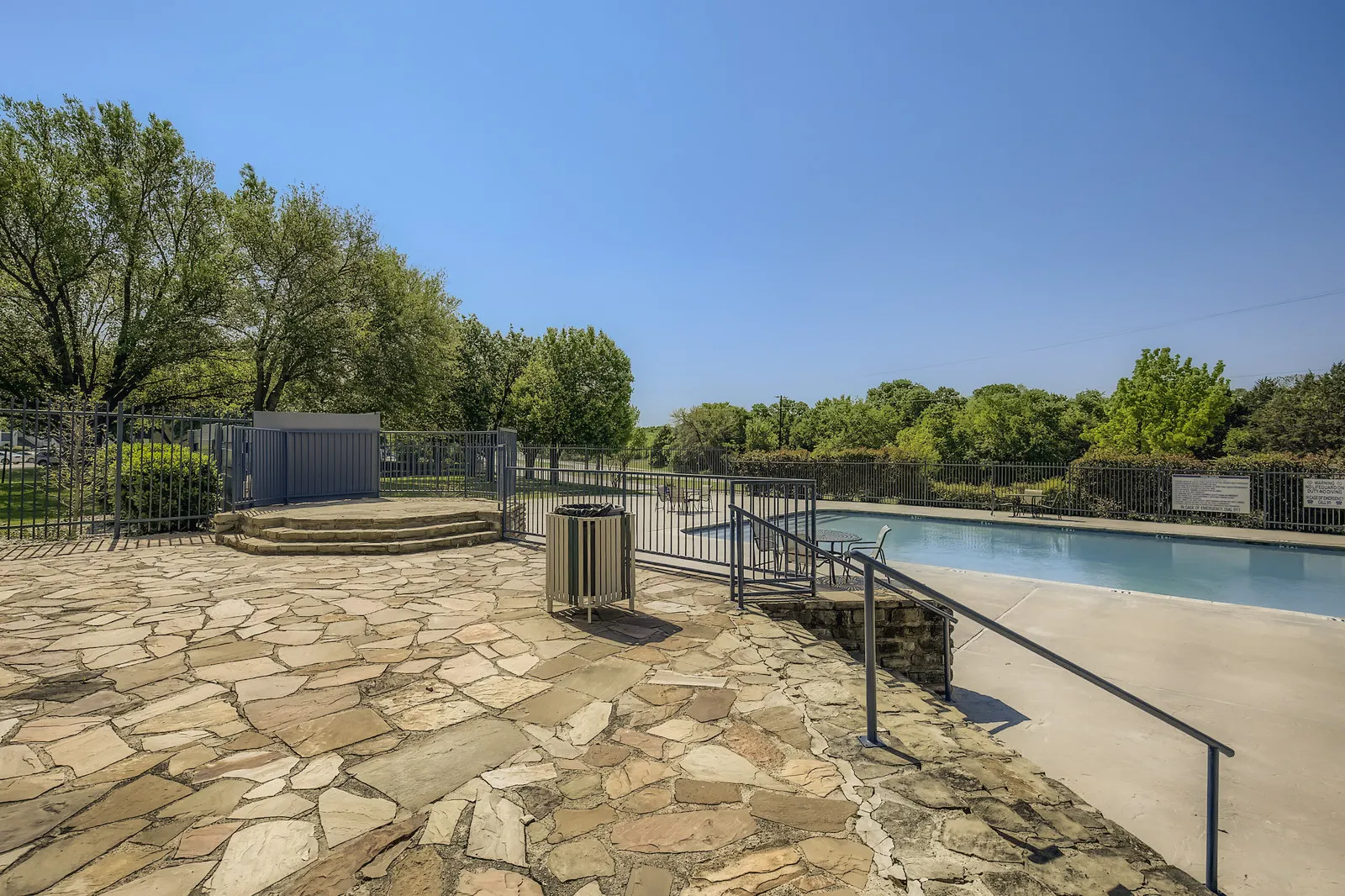 Community pool, stone patio, gated surround, mature trees