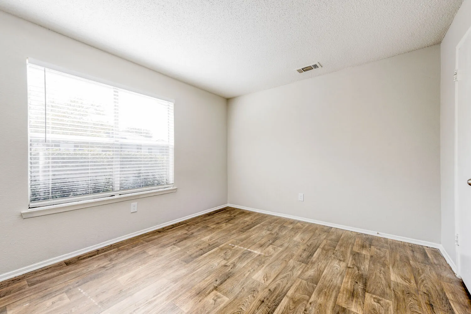 Bedroom with wood-style plank flooring, window with natural light