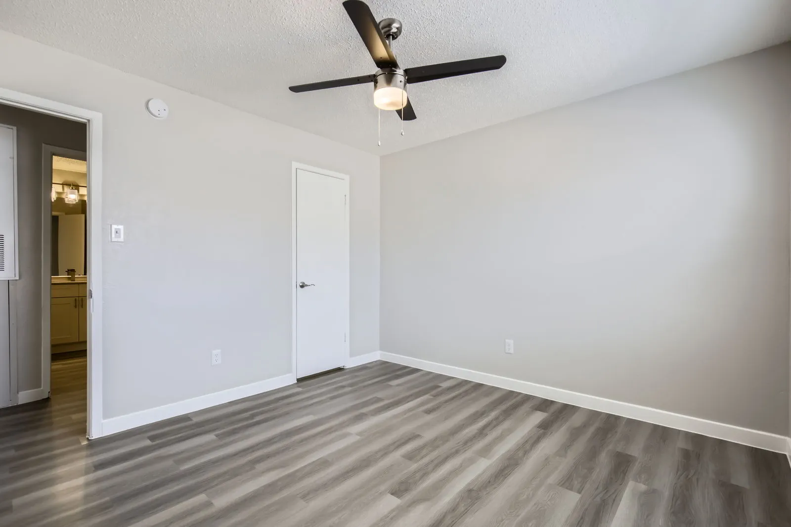 Primary bedroom with wood-style plank flooring, ceiling fan, closet door
