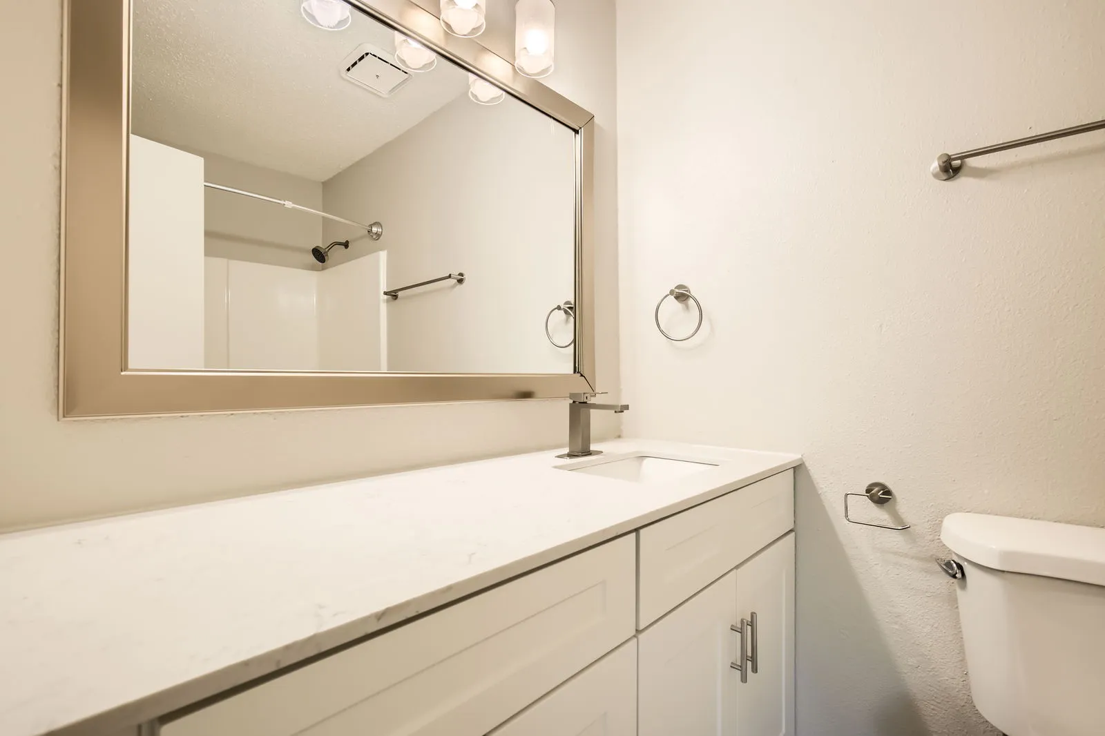 Primary bathroom, white vanity, quartz countertop, framed mirror
