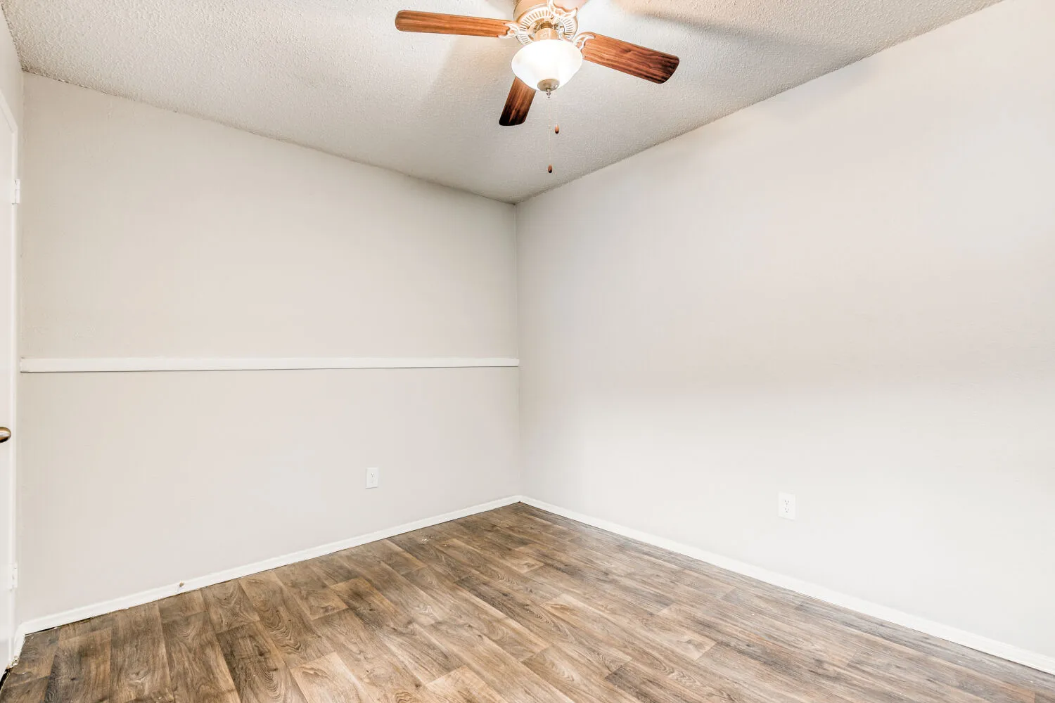 Dining area with wood-style plank flooring, ceiling fan, chair rail molding