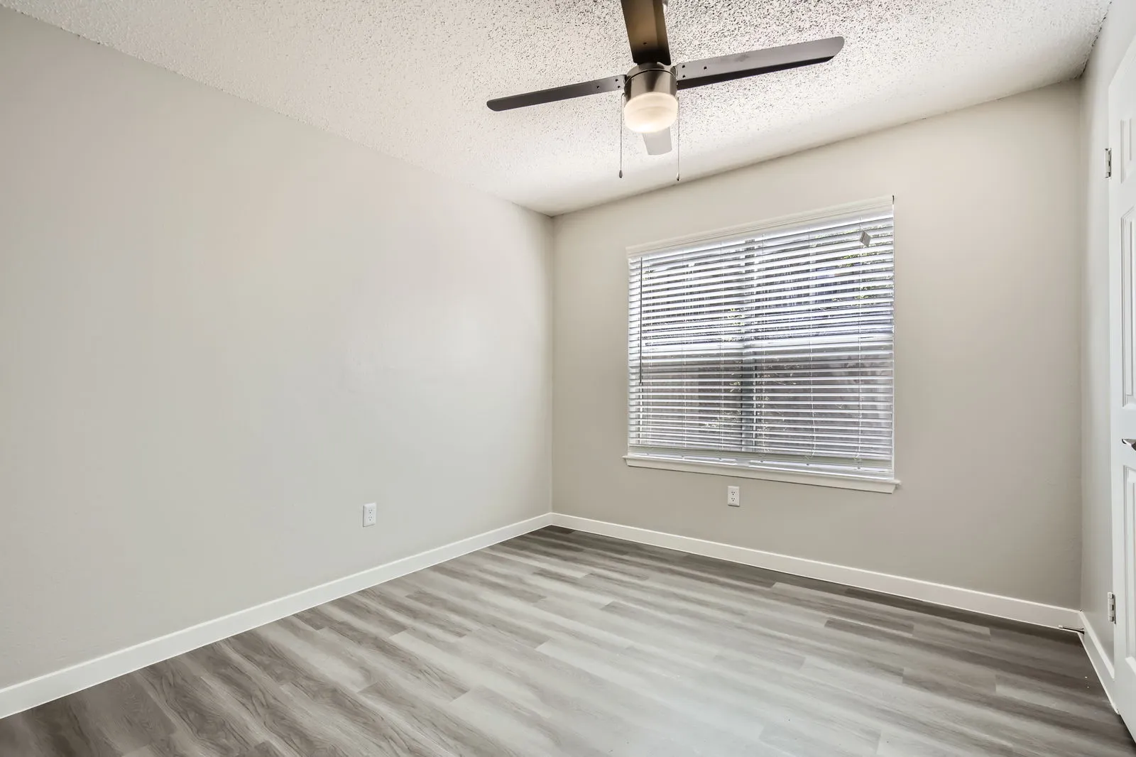 Third bedroom, wood-style plank flooring, ceiling fan, large window