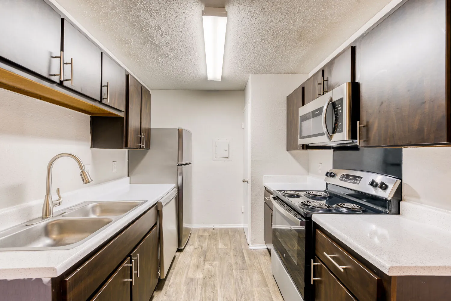 A2 Classic floor plan, kitchen with dark wood cabinetry, laminate countertops, stainless steel appliances
