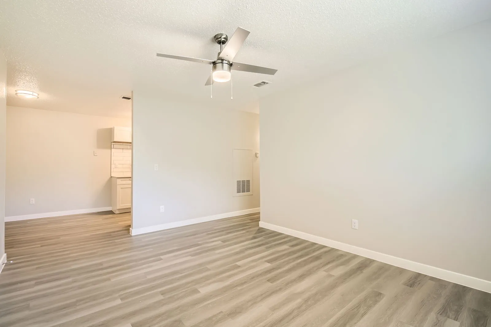 Open living area, wood-style plank flooring, view to updated kitchen