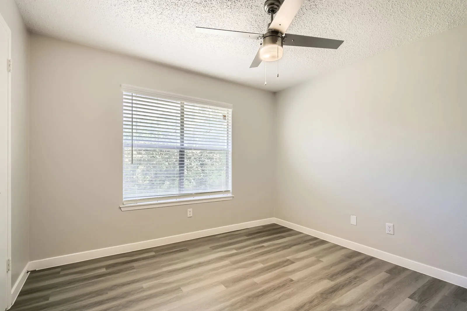 Second bedroom, wood-style plank flooring, ceiling fan, large window
