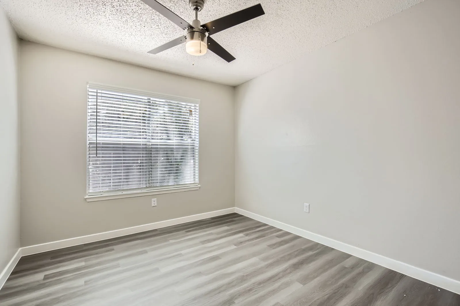 Second bedroom, wood-style plank flooring, ceiling fan, large window