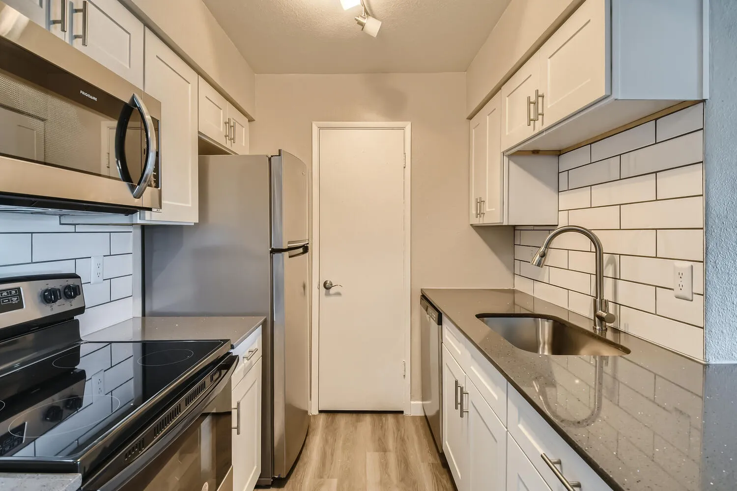 Galley kitchen, white shaker cabinets, granite countertops, stainless steel appliances