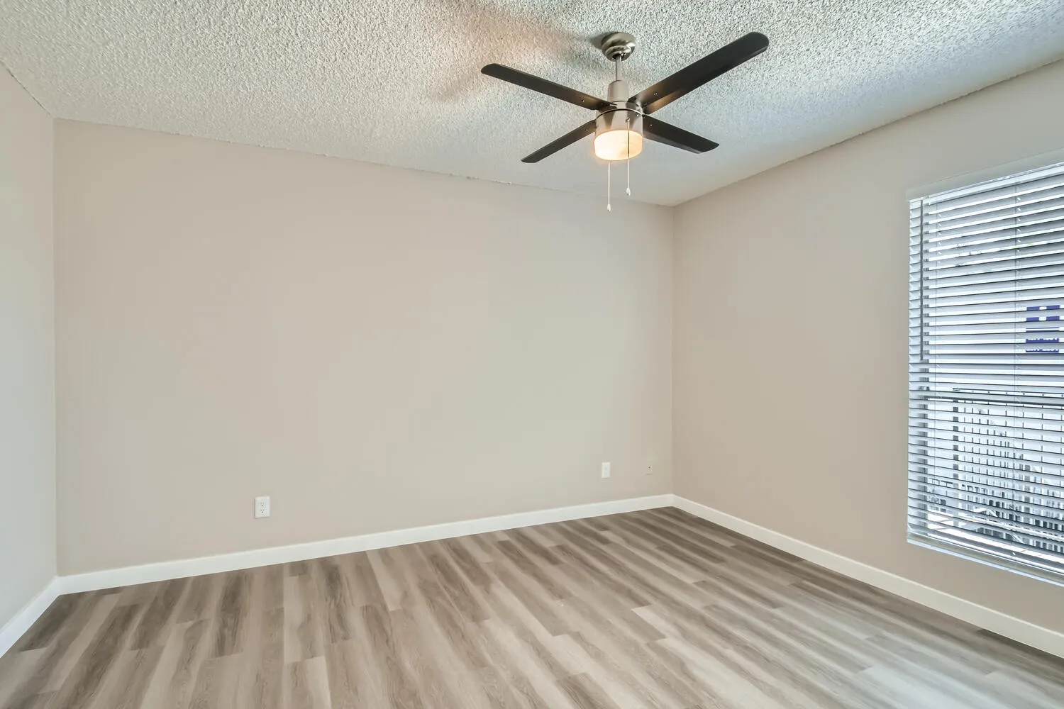 Primary bedroom, ceiling fan, mini blinds, wood-style plank flooring