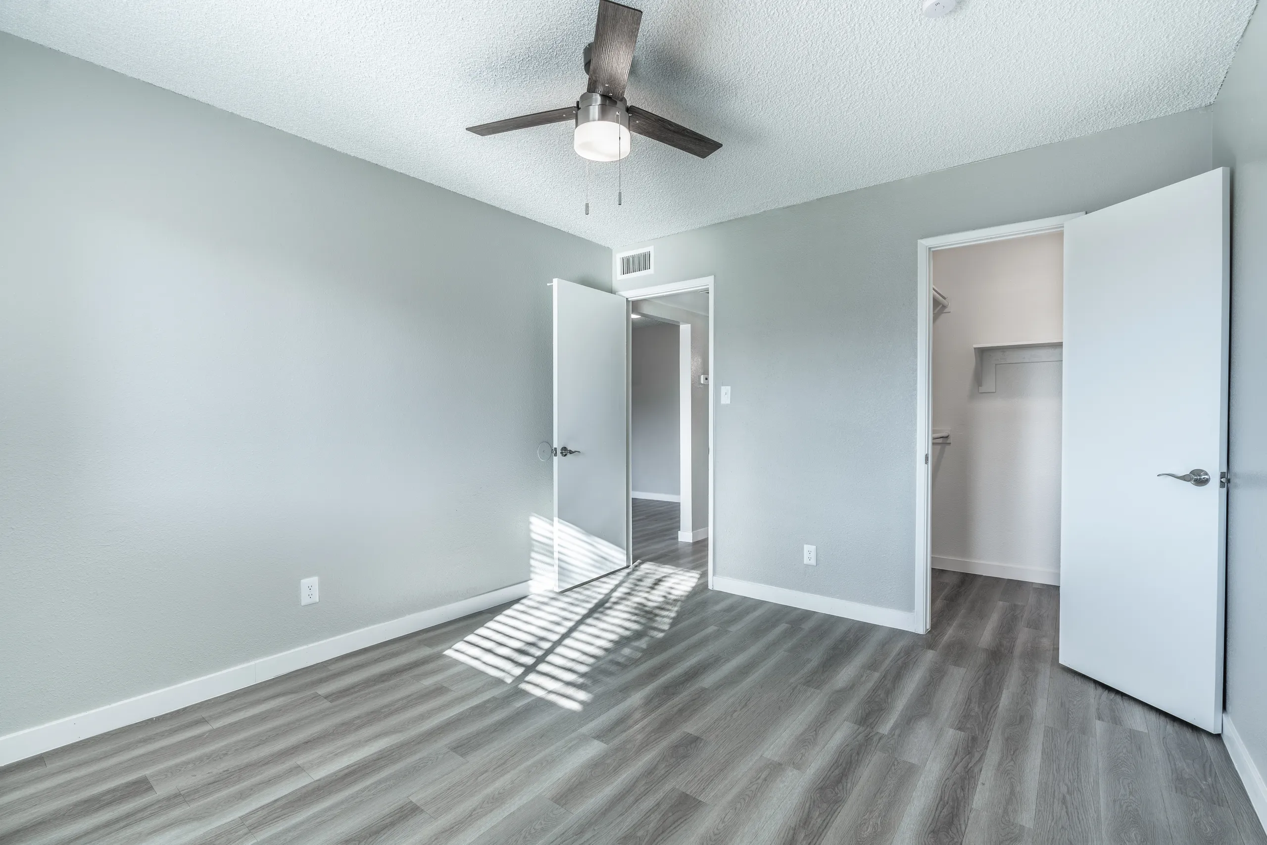 Bedroom with walk-in closet, ceiling fan, hallway entry