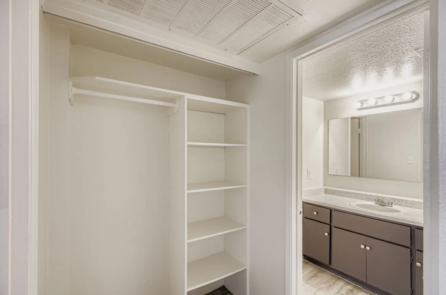 Hallway closet with shelving, view into bathroom vanity
