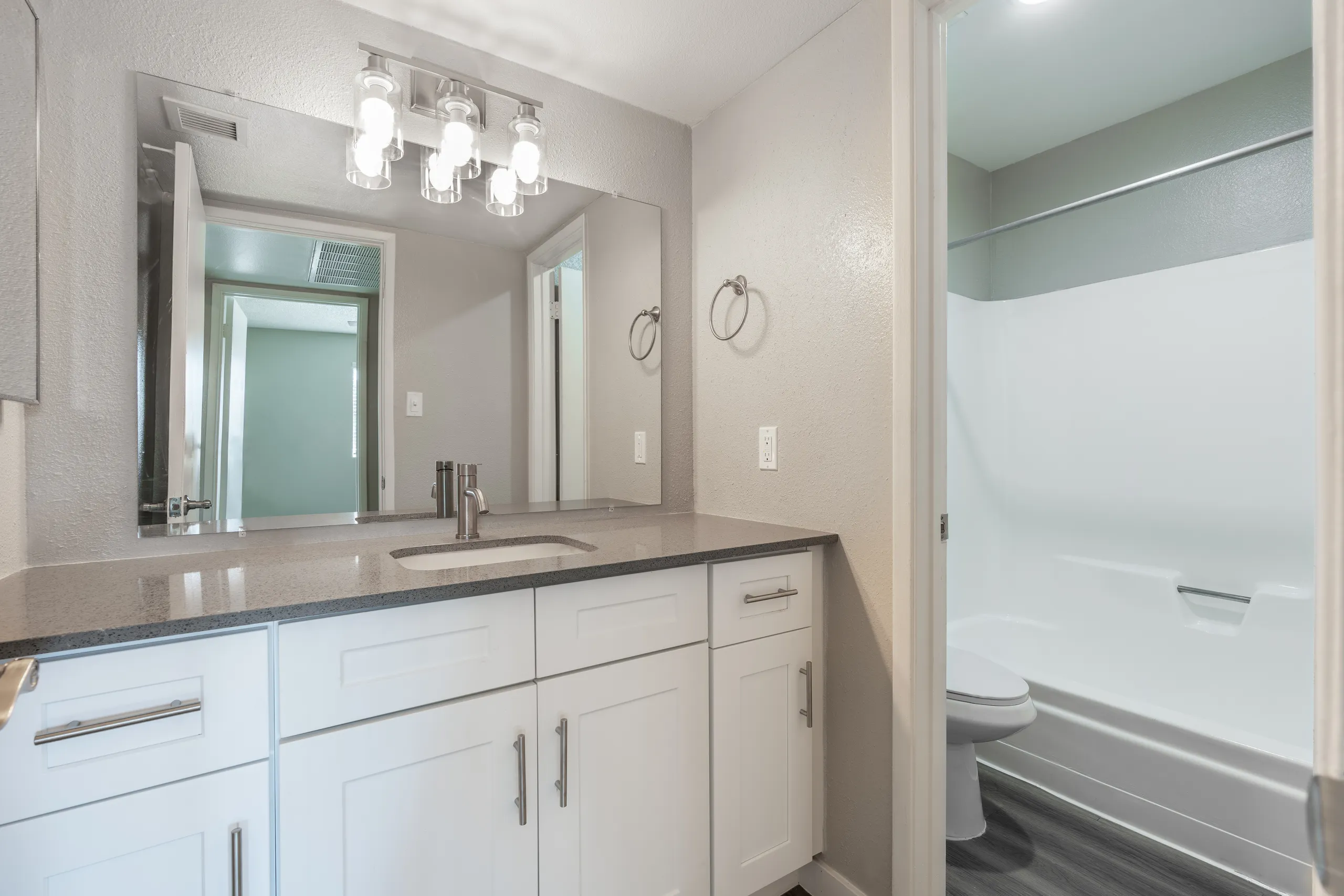 Vanity with quartz counter, framed mirror, tub/shower entry