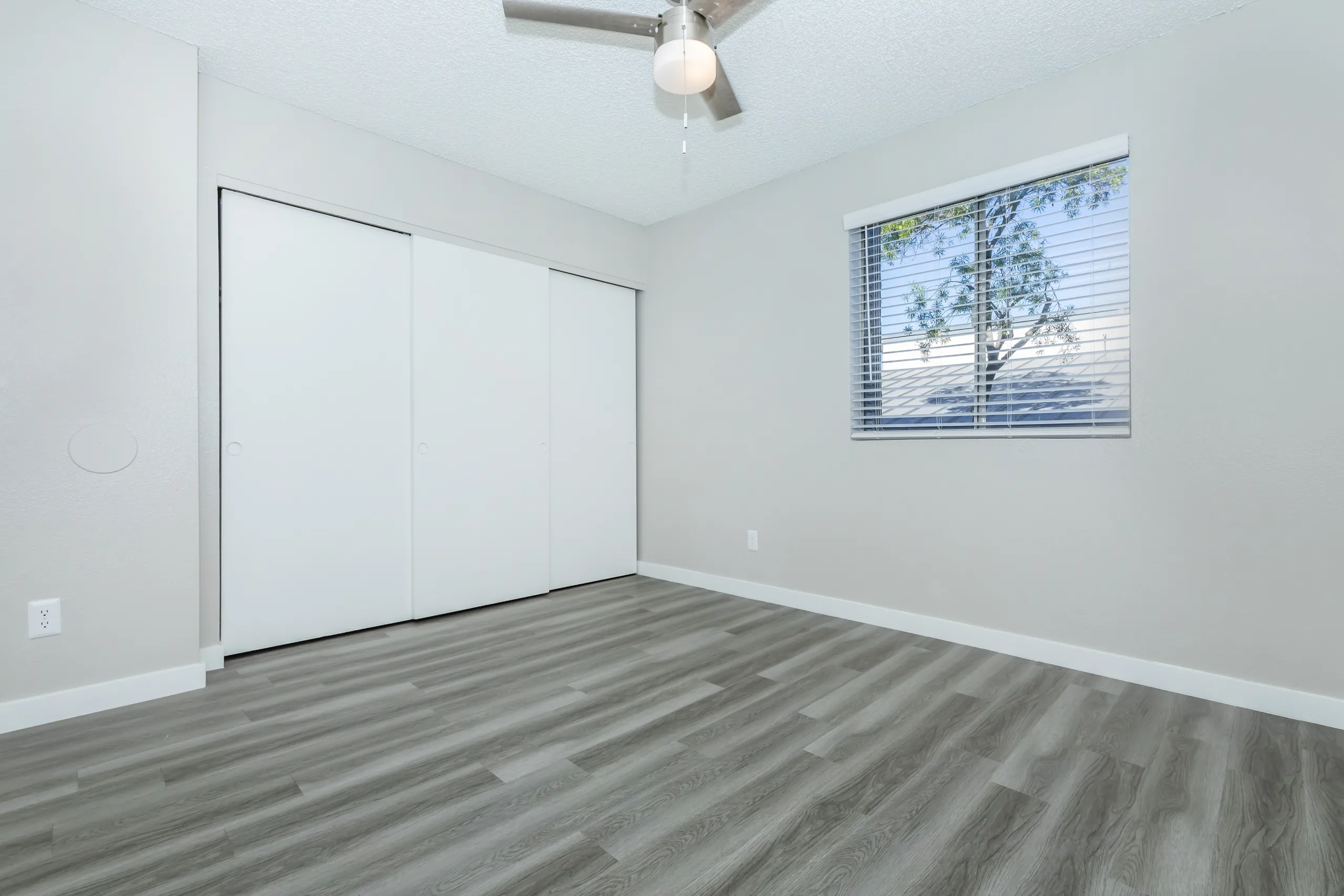 Bedroom with sliding closet doors, ceiling fan, window, wood-style plank flooring