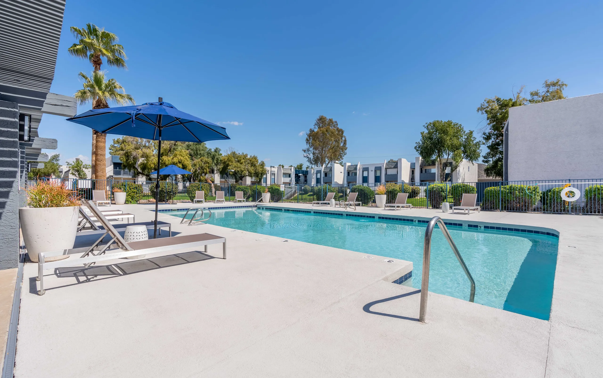Pool, lounge chairs, umbrella seating, mature landscaping