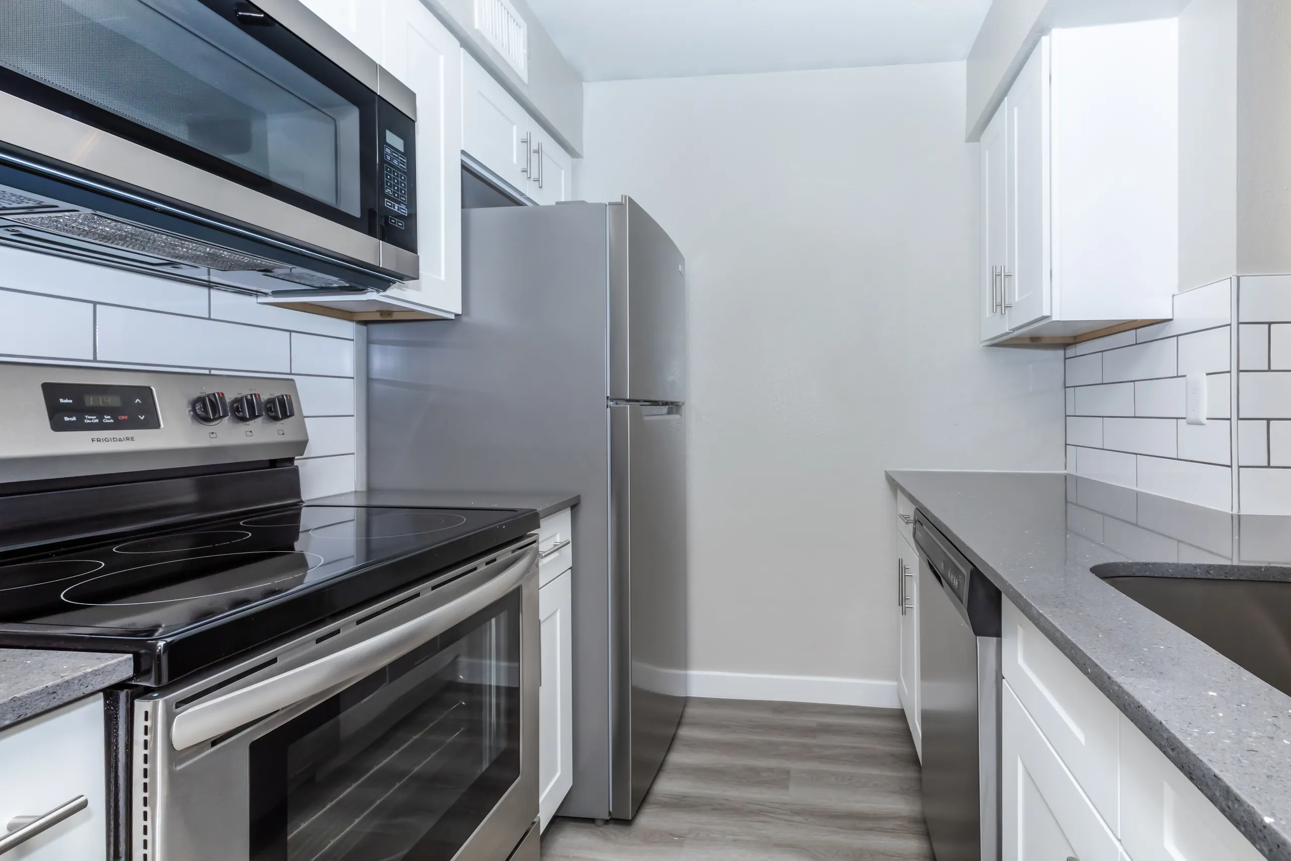 Stainless refrigerator and dishwasher, white cabinetry, subway tile backsplash