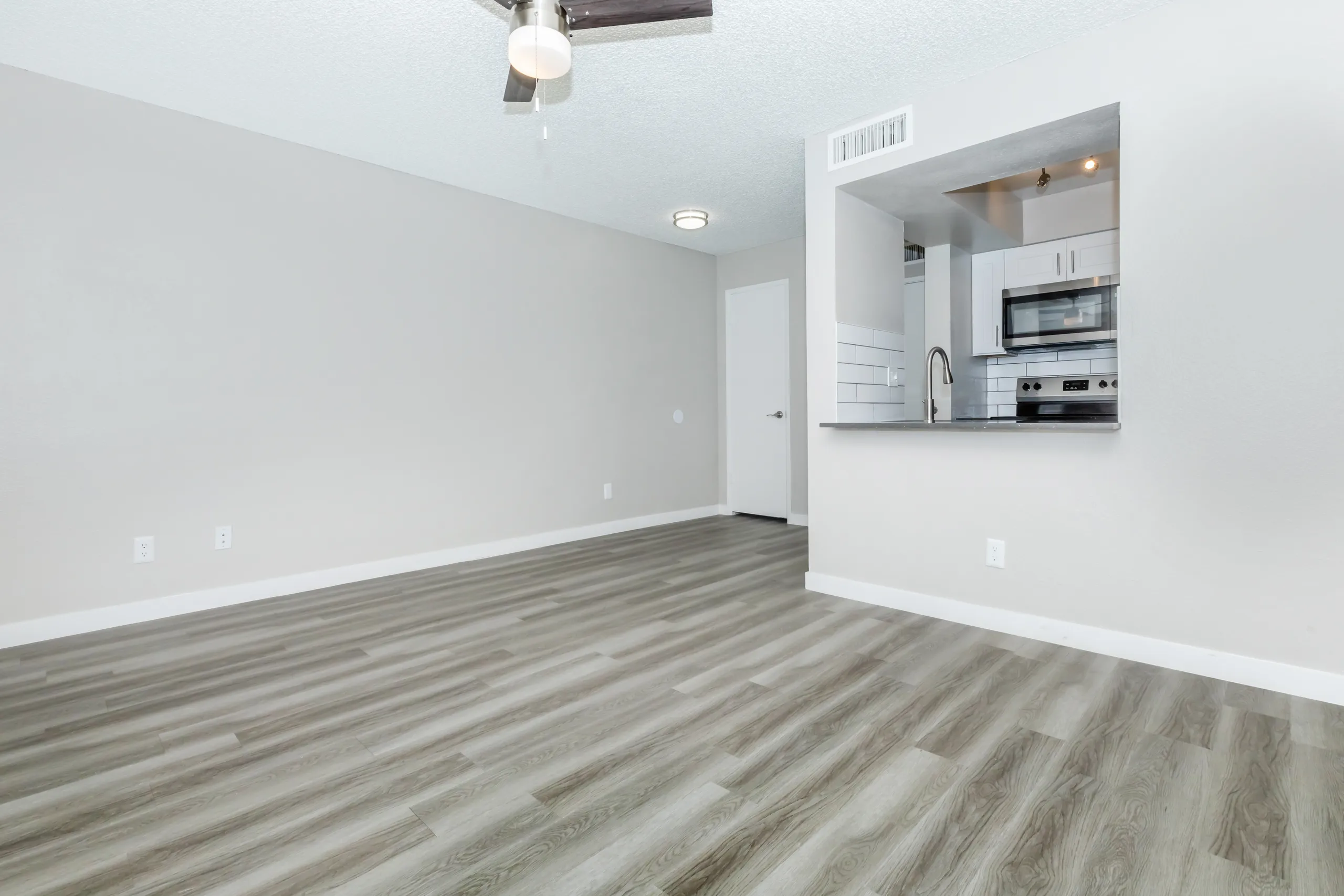Open living room, pass-through to kitchen, wood-style plank flooring