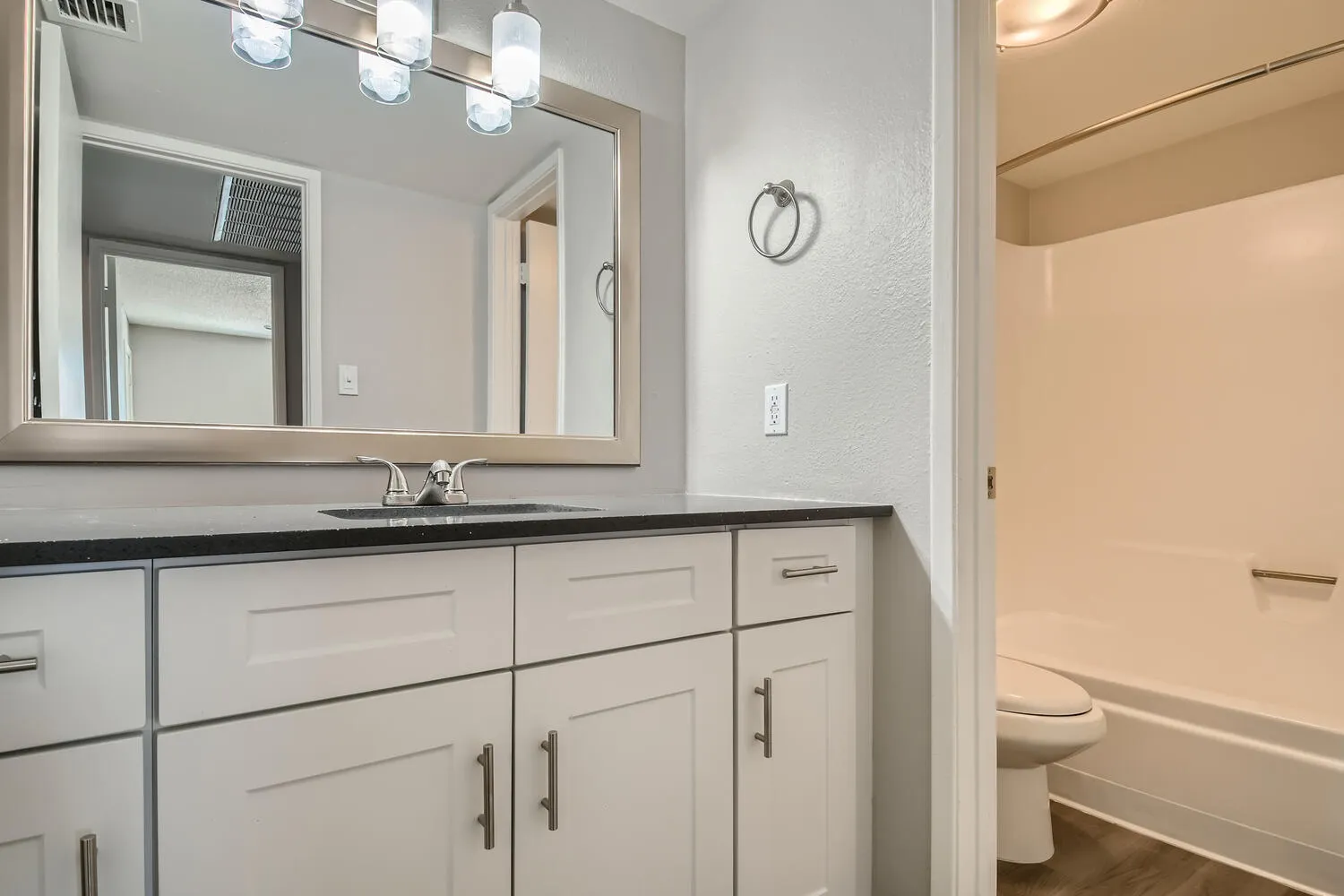 Bathroom, quartz vanity countertop, framed mirror, tub/shower combo