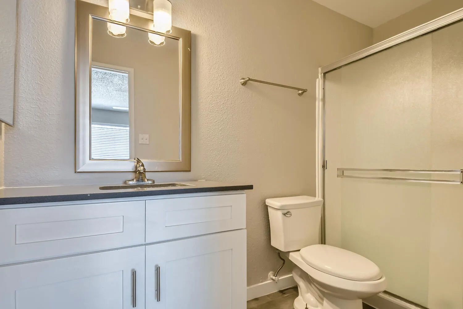 Primary bathroom, quartz vanity countertop, framed mirror, glass shower enclosure