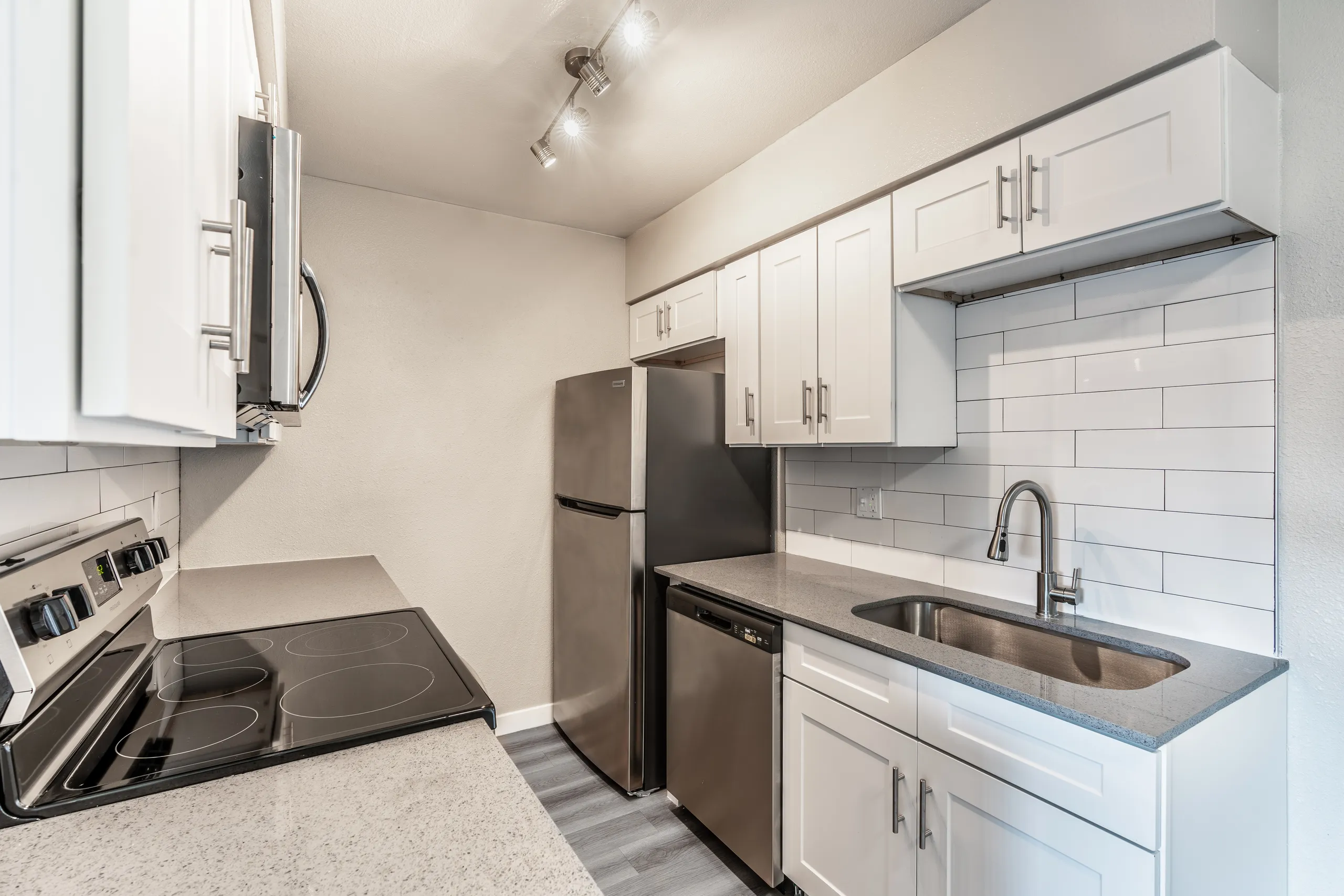 Stainless refrigerator and dishwasher, white cabinetry, subway tile backsplash