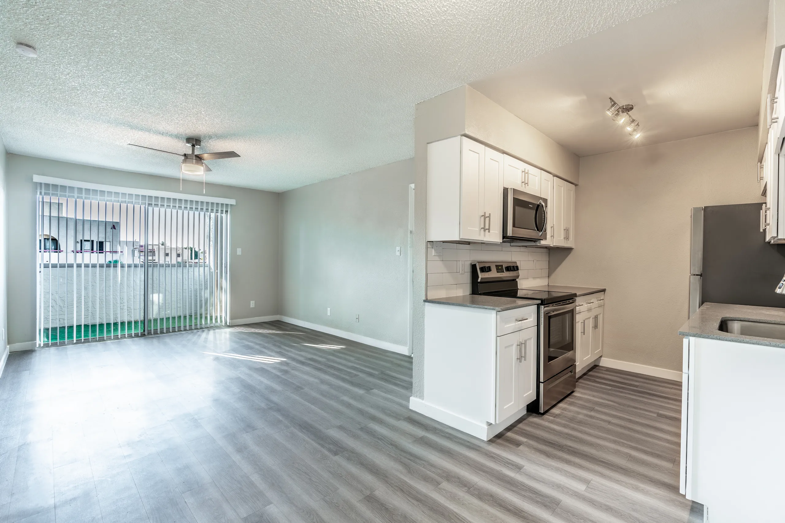 Open living area, sliding glass door, white cabinetry, stainless range